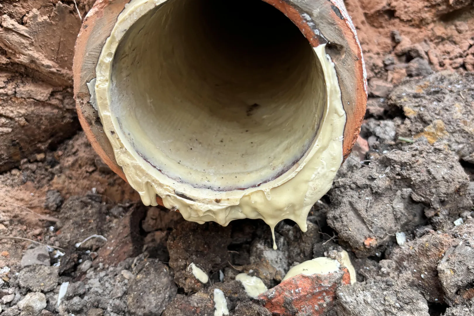 Old clay pipe with a cured liner inside, exposed in a trench