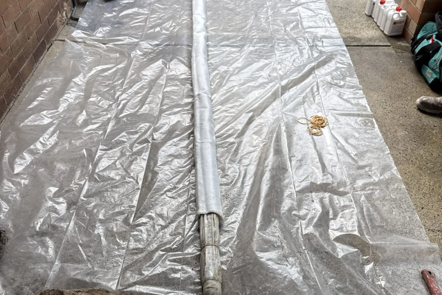 Pipe relining liner laid out on plastic sheeting in a carport