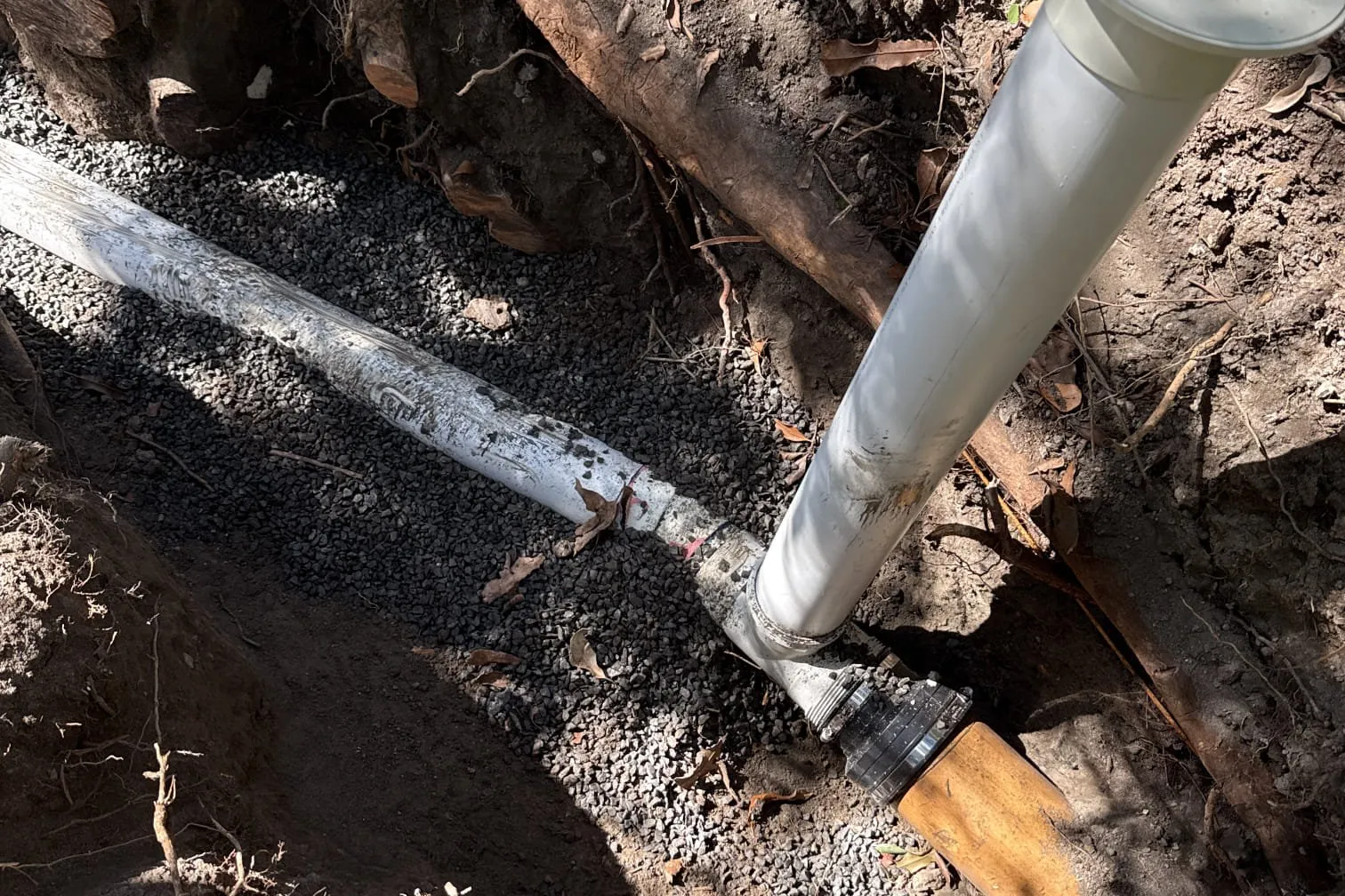 PVC pipe and a shovel in a freshly dug trench