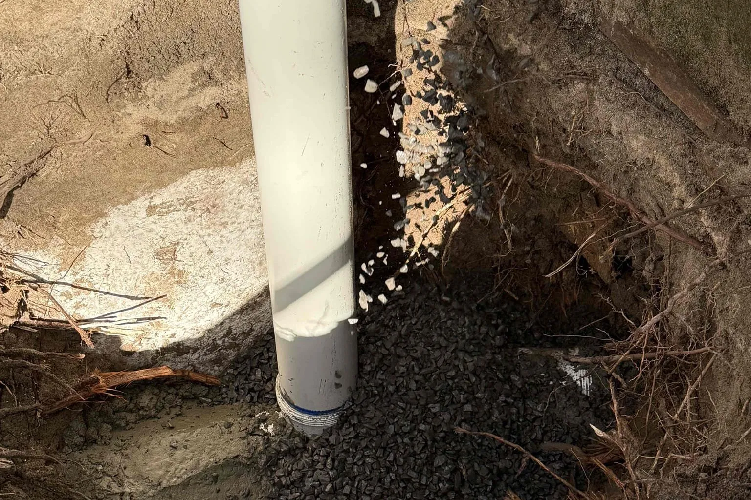 PVC riser set in an excavated hole beside a garden