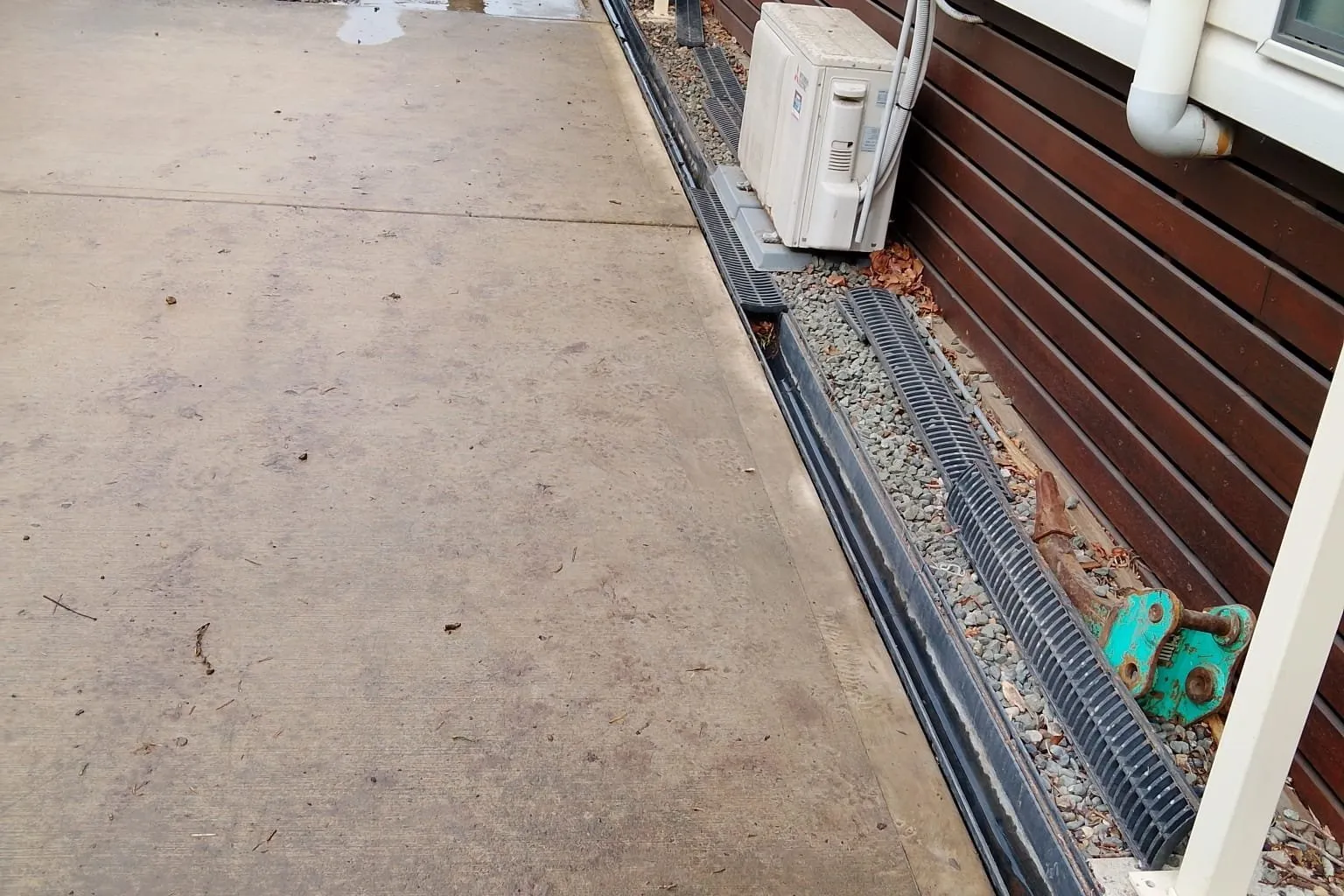 Strip drain along a concrete path beside a house